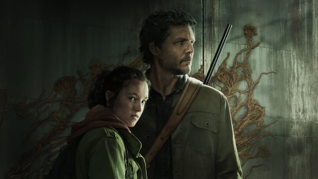 The Last of Us HBO show expands “half-developed” story: A white man with a short beard and a square jaw, wearing a green jacket, stands next to a teenage girl with black hair pulled into a ponytail. Fungus is sprouting on the cement wall behind them