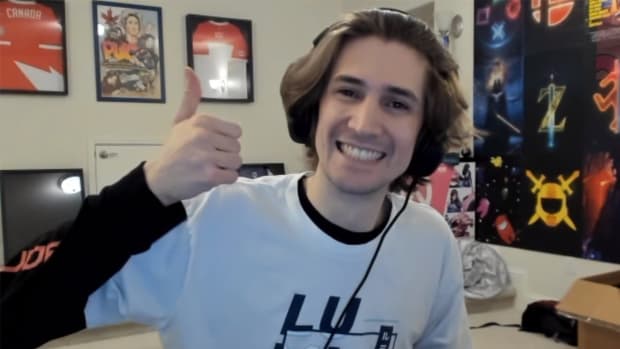 Popular streamer xQc - a young man with jaw-length blonde hair - is depicted wearing a white shirt with black sleeves. He's shown smiling and giving a thumbs-up sign with his right hand