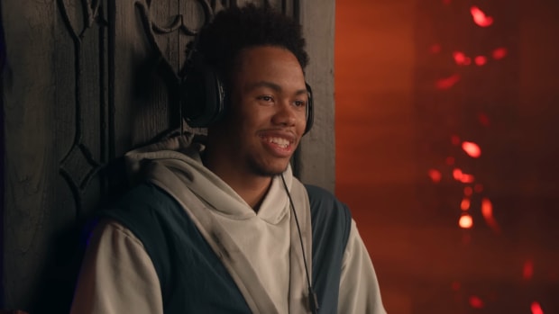 Anfernee Simons Diablo 4: Anfernee Simons, Blazers Point Guard is sitting in a tall-backed chair, wearing a grey sweatshirt and a headset.