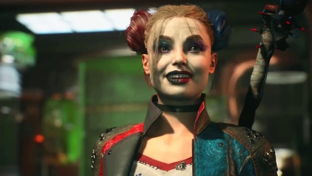 Suicide Squad's Harley Quinn, in her signature patched jacket and red-and-blue hair buns, is standing in an underground bunker. She wears a look of excited anticipation on her face