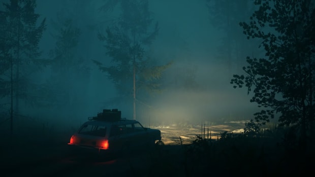 A car heads down a road by its headlights cutting through a foggy forest
