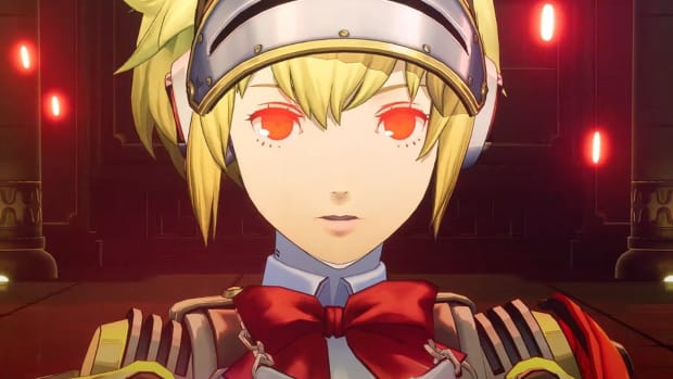 Persona 3 Reload's Aigis, in her Answer outfit, standing in a metal room lit by bright red lamps