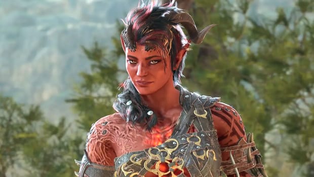 A red-skinned woman with horns and pointy ears, and flames burning in her chest, is standing in a forest with a sly smile on her face