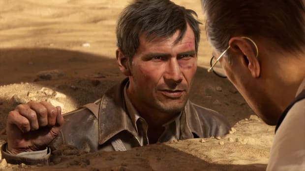 An animated version of a young Indiana Jones is submerged in sand up to his neck, with only his right hand and his head visible.