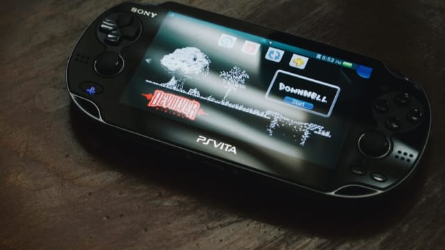PS Vita on a dark wood table.