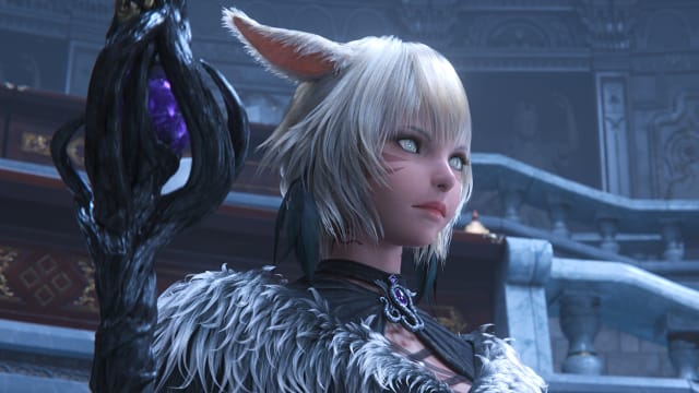 Final Fantasy 14's Y'shtola, in her late-game robe, is standing in a stone courtyard with a large black staff housing a purple gem at its core.