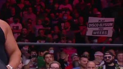 Sign at an AEW show that says "Play Disco Elysium, you weebs"