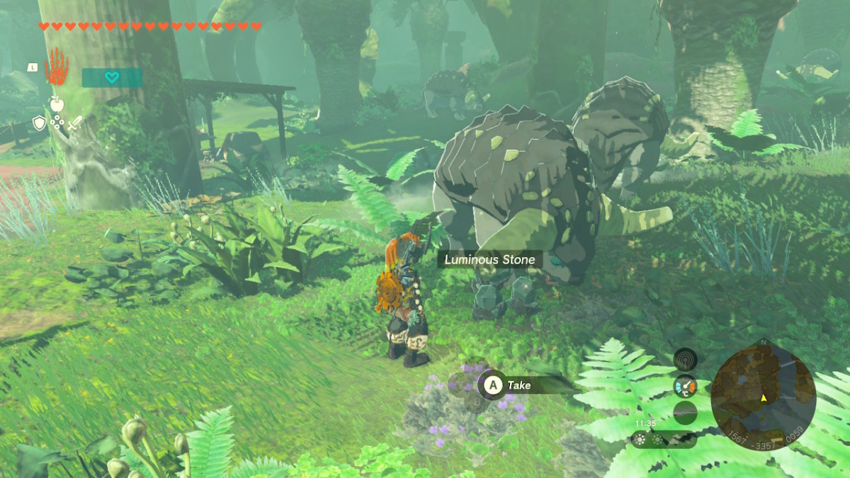 A screenshot of Link in Tears of the Kingdom standing next to a large, cow-like creature in a lush forest. On the ground is an object labelled Luminous Stone, and a prompt appears on screen to take the object.