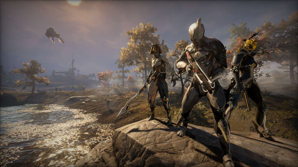 Three cyborg ninja stand together close to a forest in Warframe.