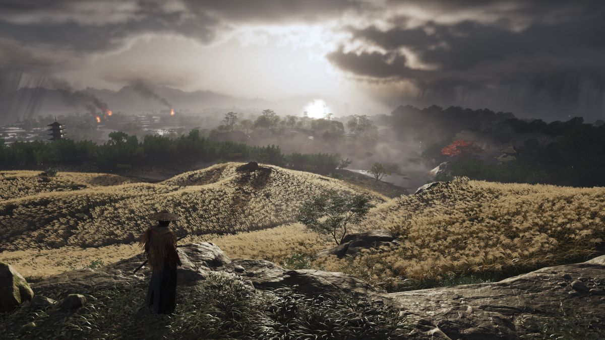 A samurai stands overlooking fields undeneath an overcast sky in Ghost of Tsushima.