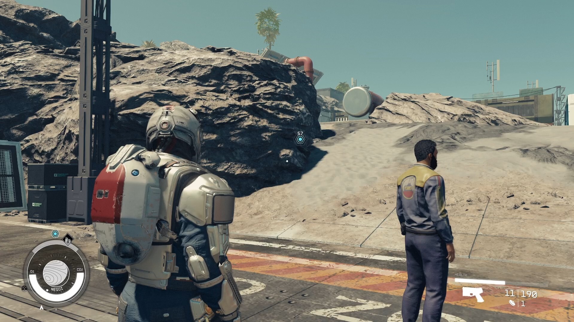 The main character stands behind companion Barrett on a dusty planet in Starfield.