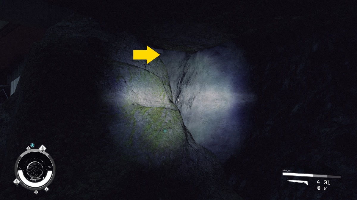 Artificial light illuminates a rocky crevice, with a yellow arrow at the top pointing out a path forward that's straight ahead