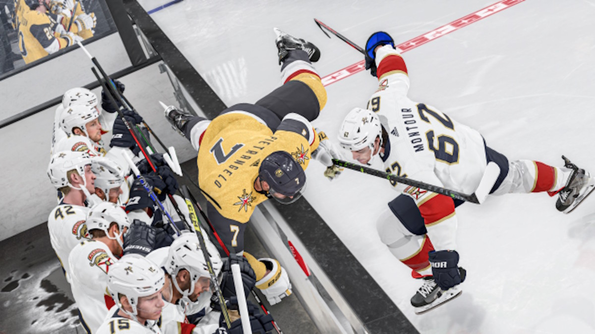 A hockey player is shoving an opposing player over the wall, into the benches beyond.