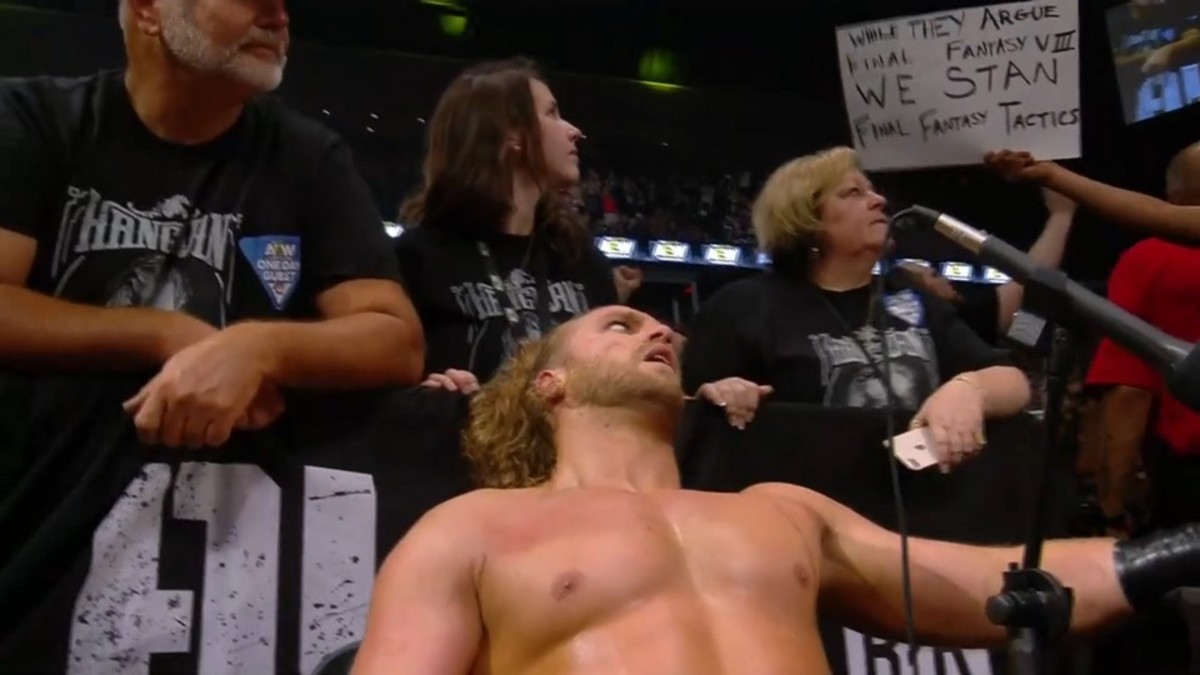 Adam Page looking at an AEW fan sign that says "While they argue Final Fantasy VII we stan Final Fantasy Tactics"