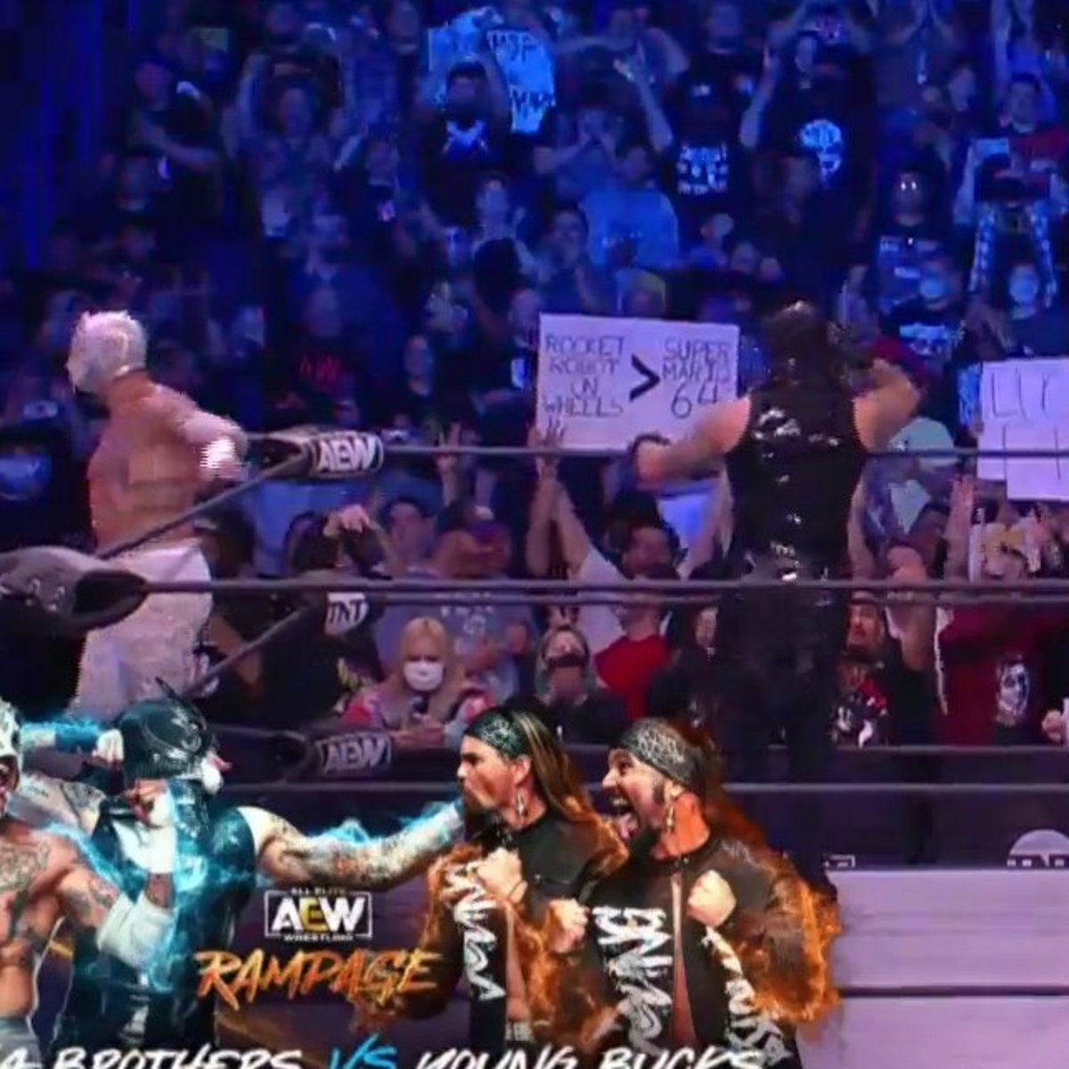 AEW fan sign that says "Rocket Robot on Wheels > Super Mario 64" behind the Lucha Brothers