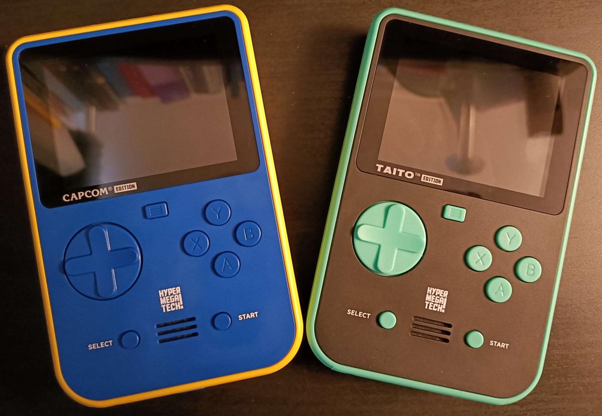 A photo of the Capcom and Taito Super Pocket handheld consoles side by side.